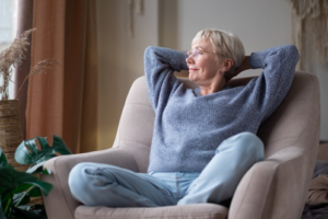 Senior woman resting on comfy chair during dental implant recovery