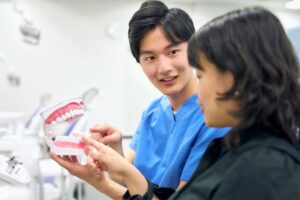 Patient and periodontist looking at tooth model